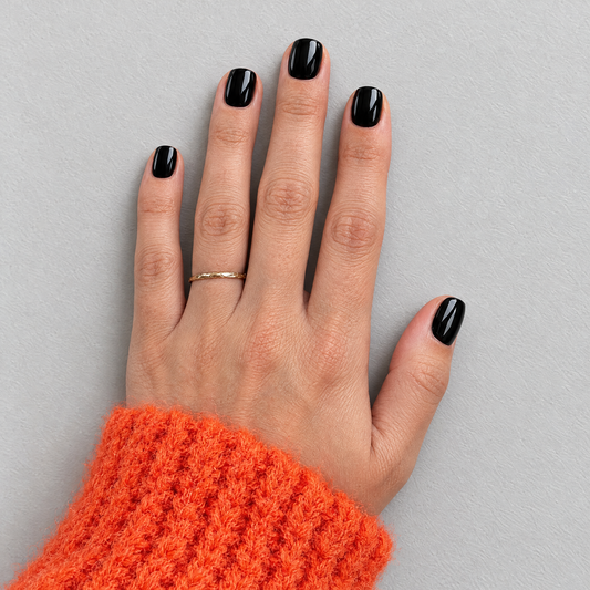 Black Tie (Extra-Short) glossy black press-on nails, overhead flat lay with orange knit sleeve