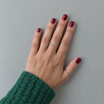 After Dark (Extra-Short) glossy burgundy press-on nails in an overhead flat lay with a forest-green knit sleeve